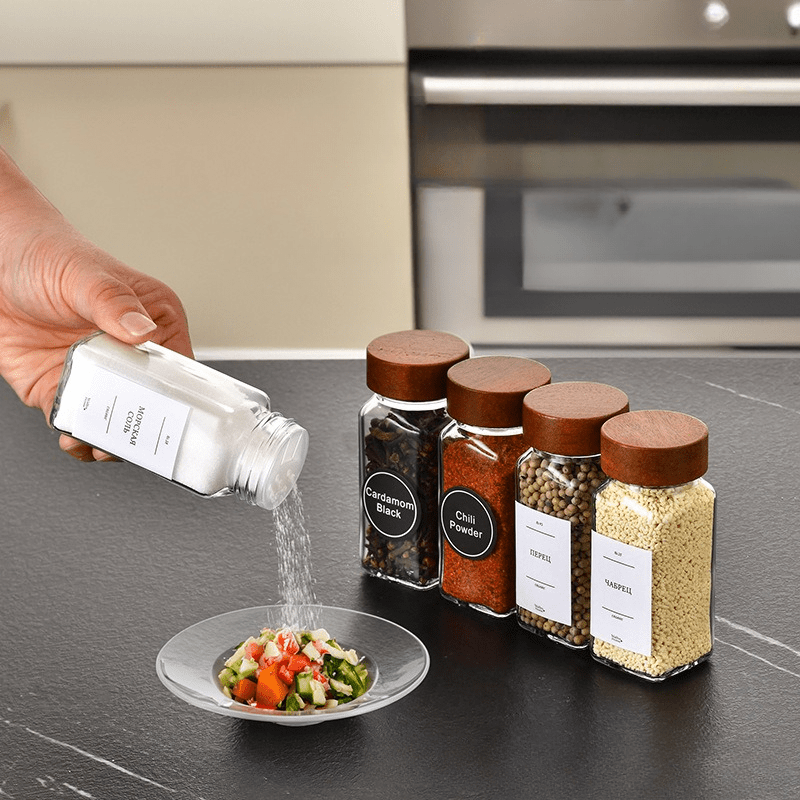 Acacia wood spice jars set with various spices being poured over fresh salad in a kitchen