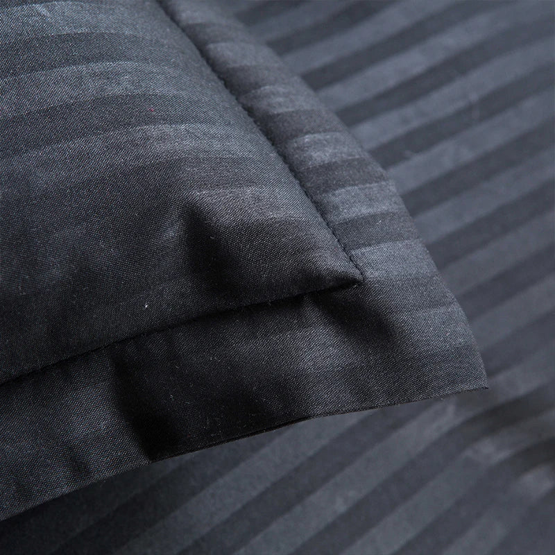 Close-up of black satin duvet cover set with subtle striped pattern and smooth texture