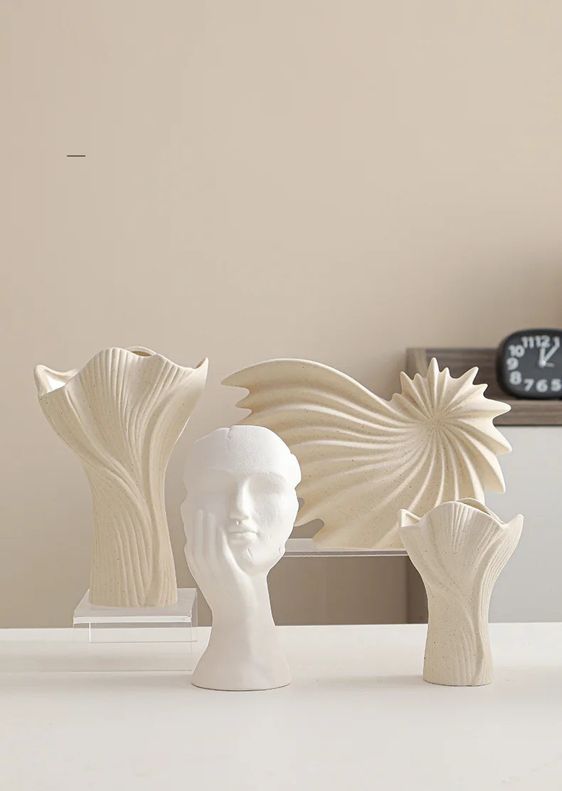 Nutshell ceramic conch design vase displayed with sculptural ceramic vases on white surface