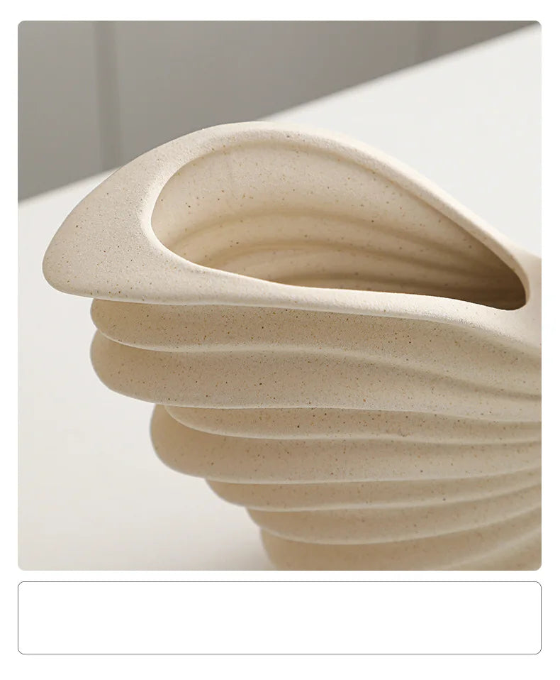 Nutshell beige ceramic conch design vase with smooth curved ridges and hollow interior