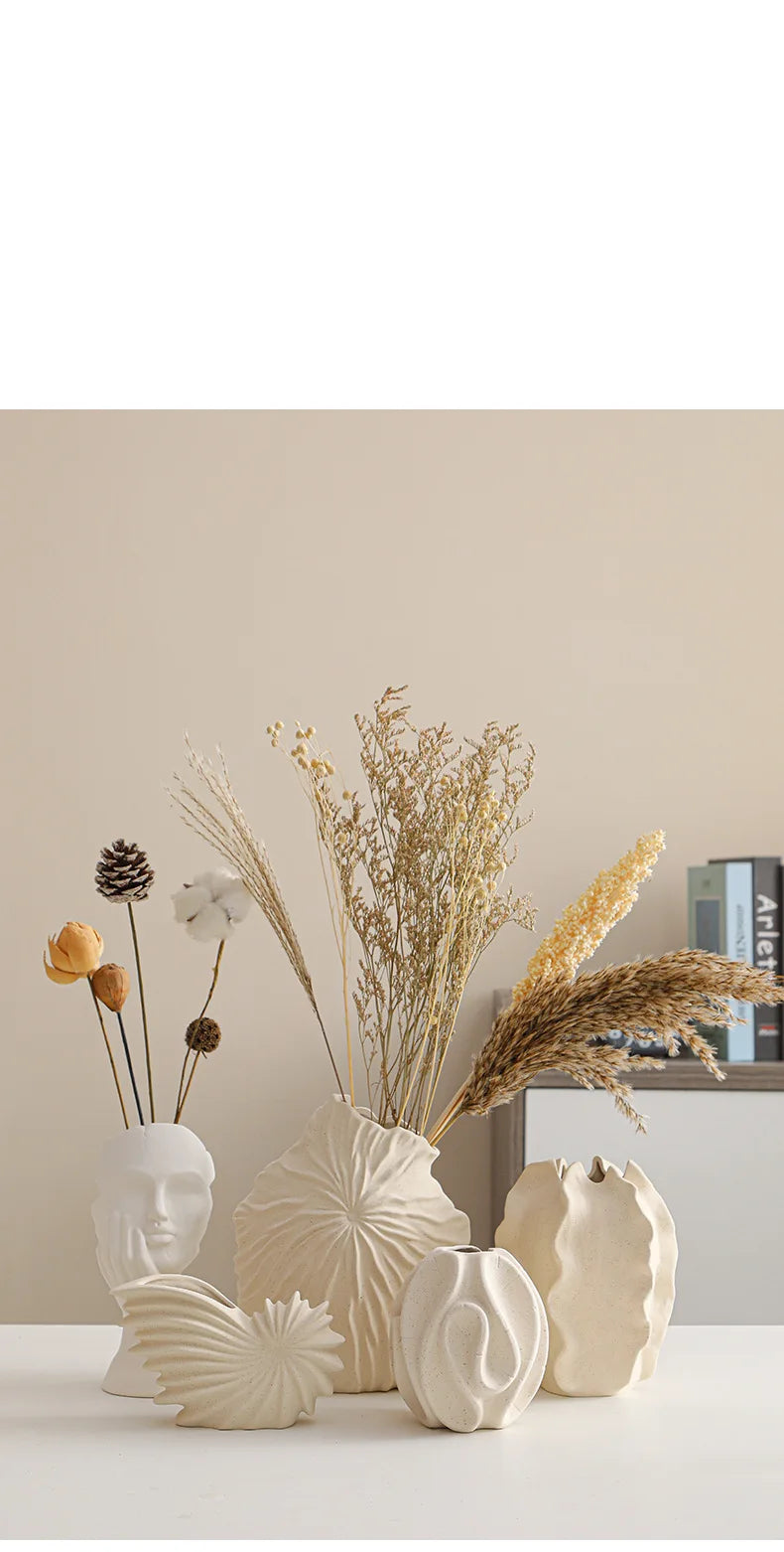 Ceramic conch design vase by Nutshell with dried flowers and matching decorative vases on white surface