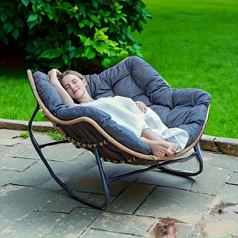 Woman relaxing on a gray comfortable patio chair cushion in round rocking lounge chair on stone patio