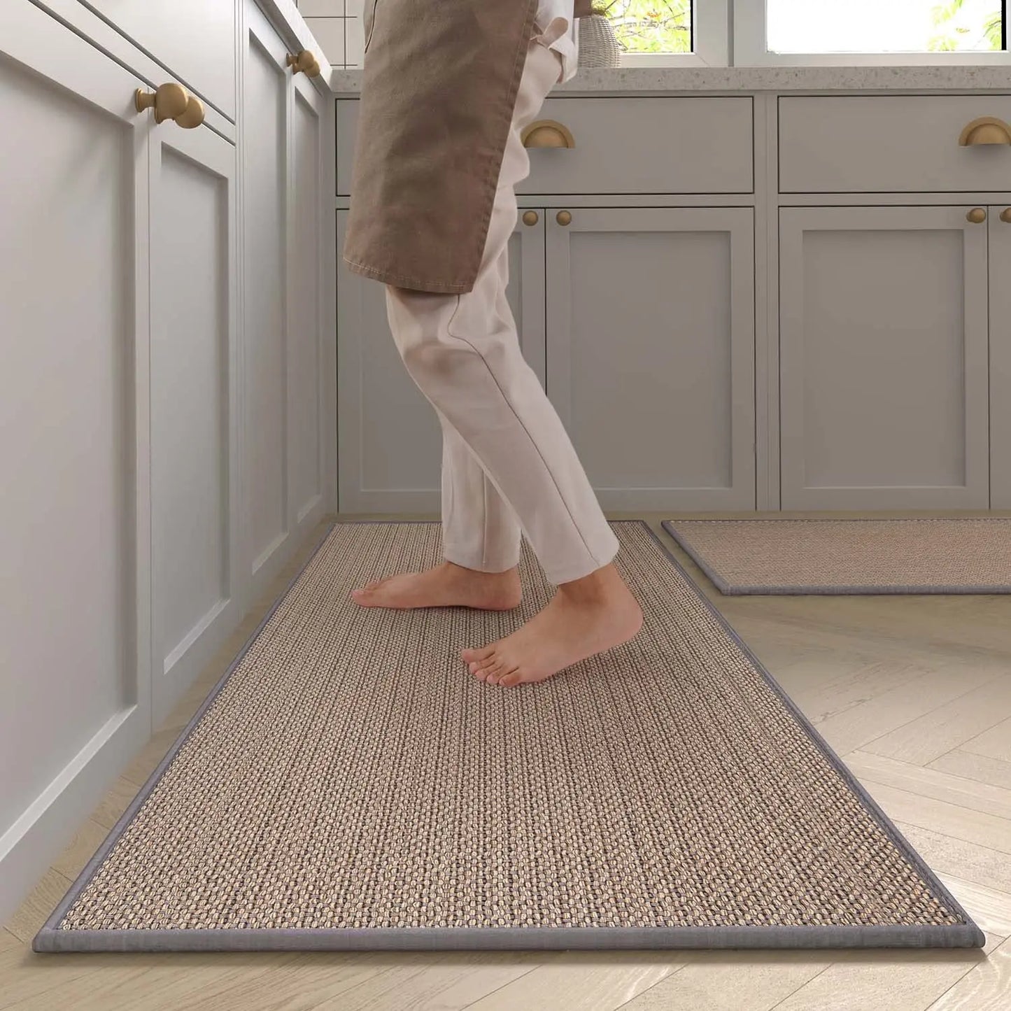 Nutshell washable non-slip kitchen rug runner in tan woven texture under barefoot person by gray cabinets
