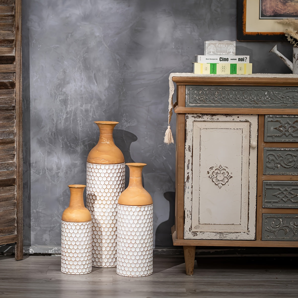 Three decorative extra large metal floor vases with a textured white body and tan neck, styled beside a vintage cabinet