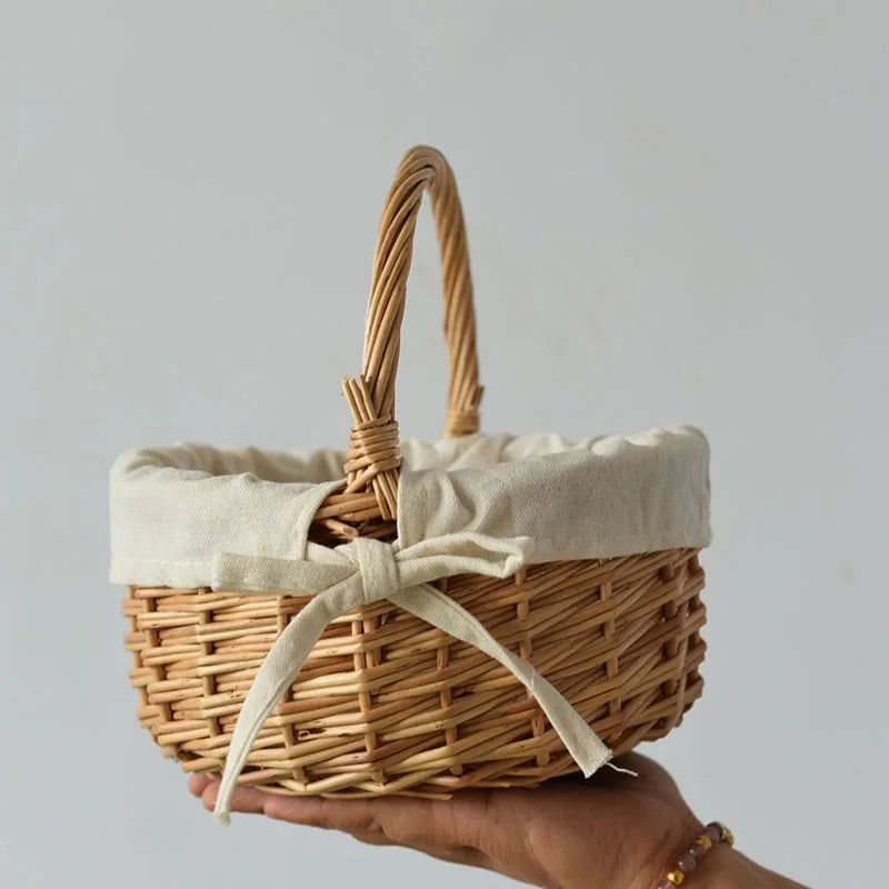 Hand holding a handcrafted wicker basket with a fabric liner and bow by Nutshell