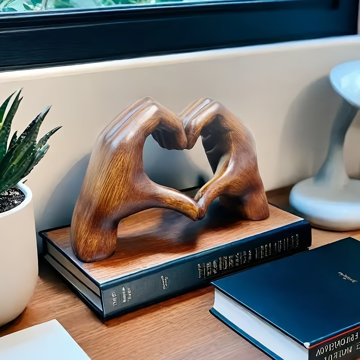 Heart-shaped resin sculpture decor by Nutshell shaped as two hands forming a heart on a wooden desk