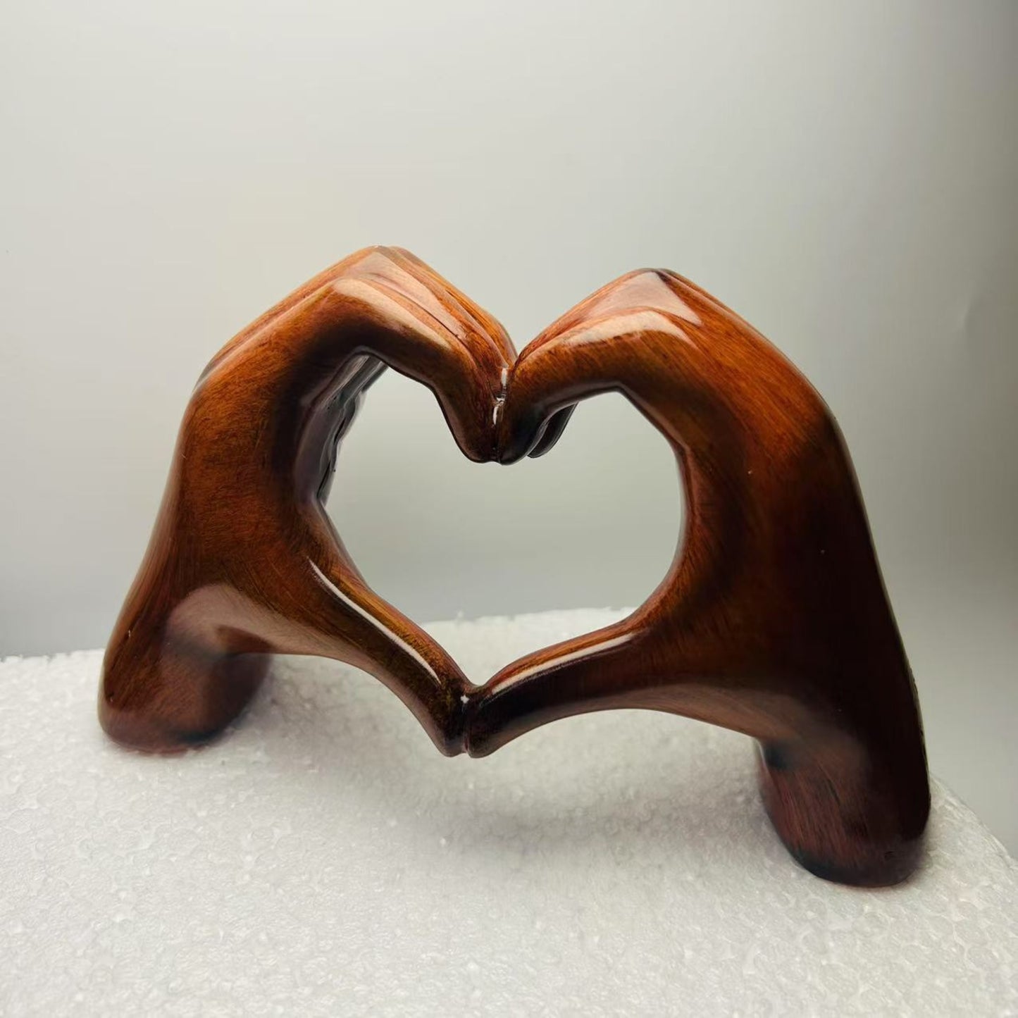 Nutshell heart-shaped resin sculpture decor featuring two hands forming a heart in dark brown finish