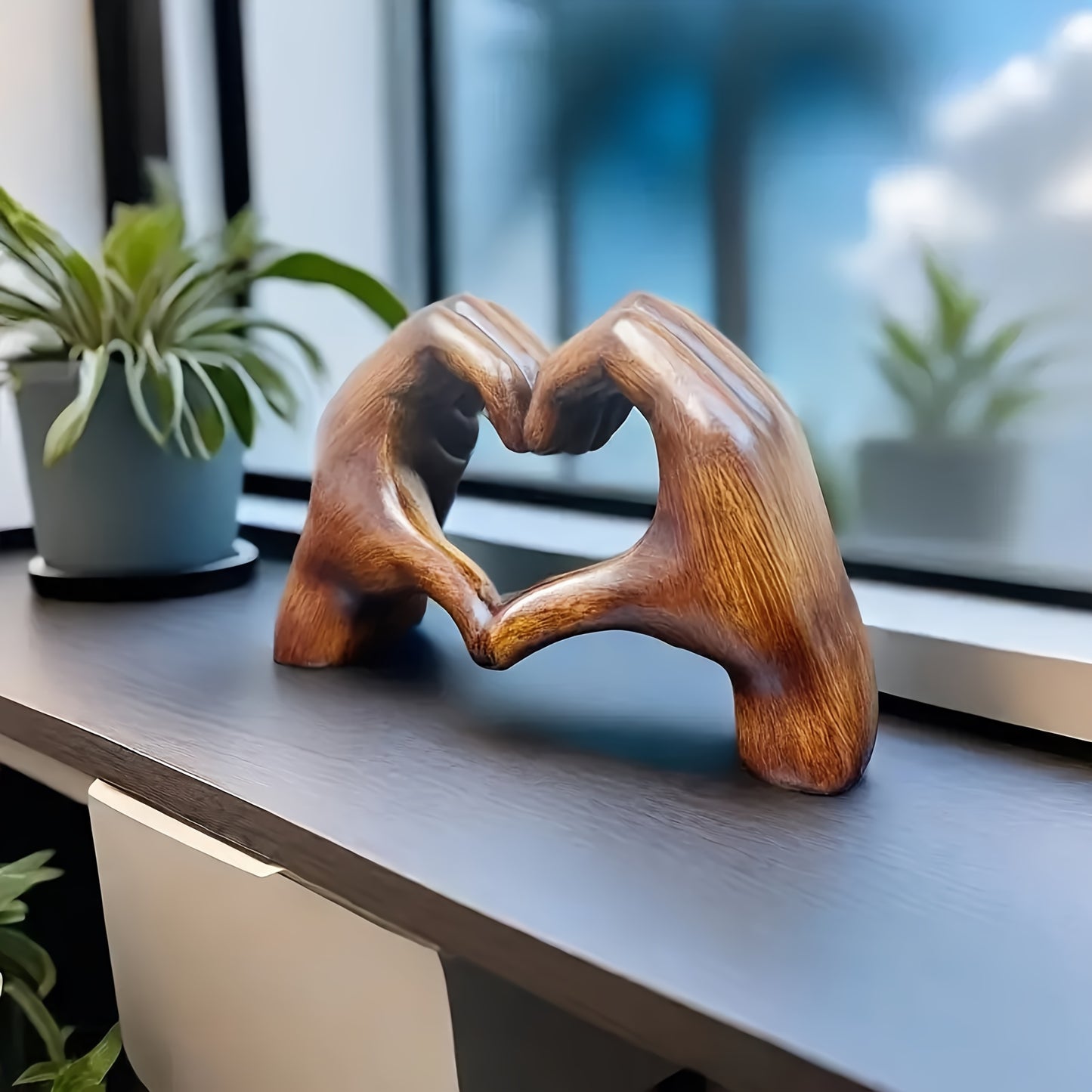 Heart-shaped resin sculpture decor by Nutshell featuring two wooden hands forming a heart on a windowsill