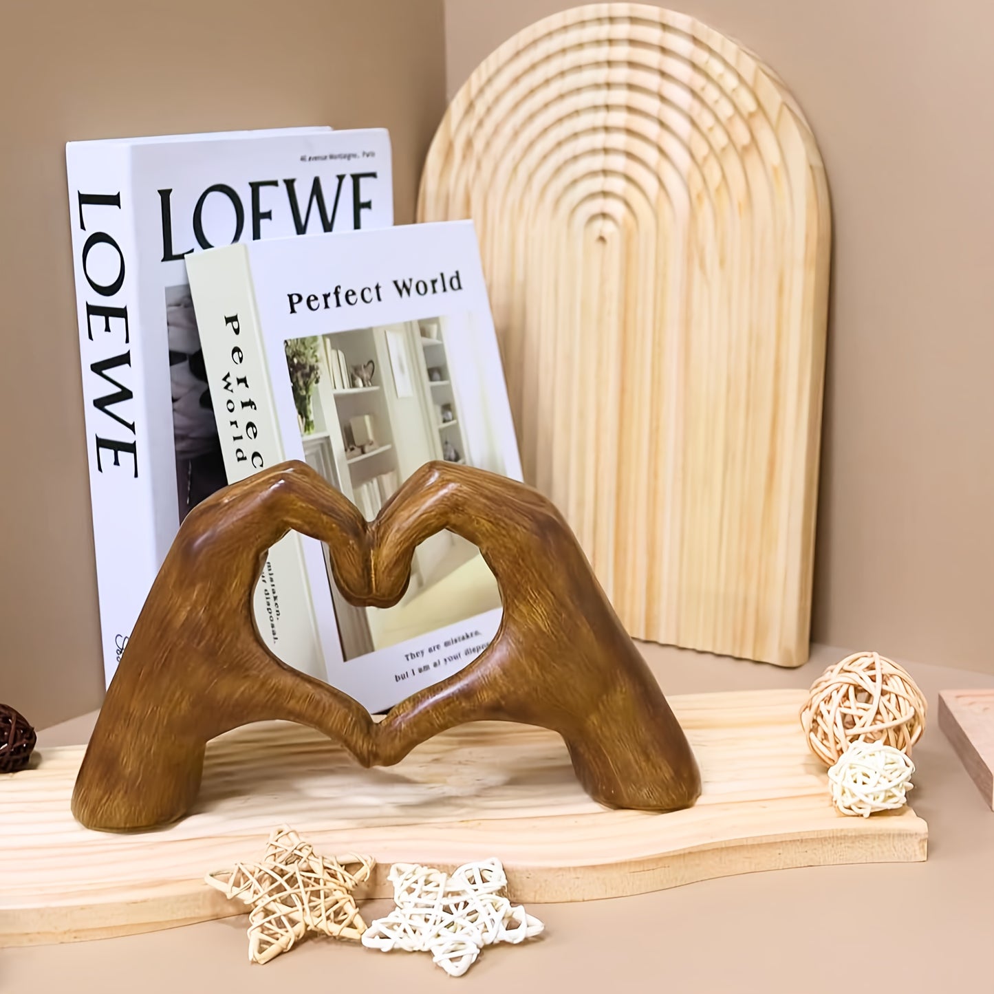 Heart-shaped resin sculpture decor of two hands forming a heart on wooden shelf with books and decorative stars