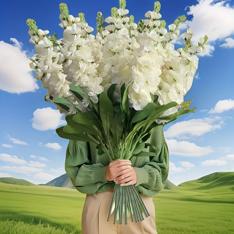 Large outdoor artificial delphinium bouquet held by a person against a green landscape backdrop
