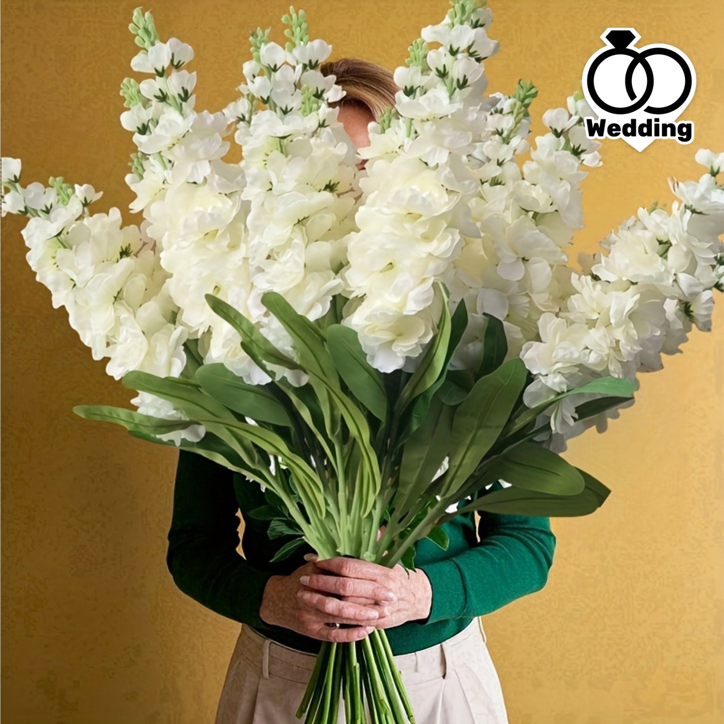 Large outdoor artificial delphinium bouquet held by a person, featuring lush white blooms and green foliage