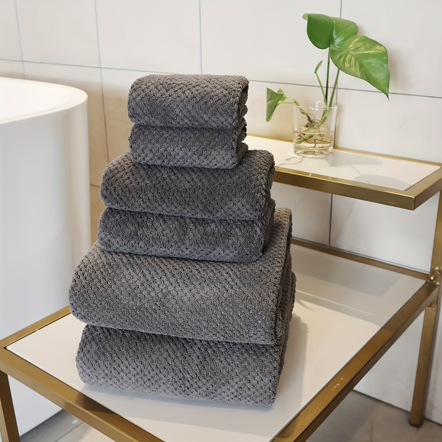 Luxury bath towel set in gray stacked neatly on a gold and white bathroom table
