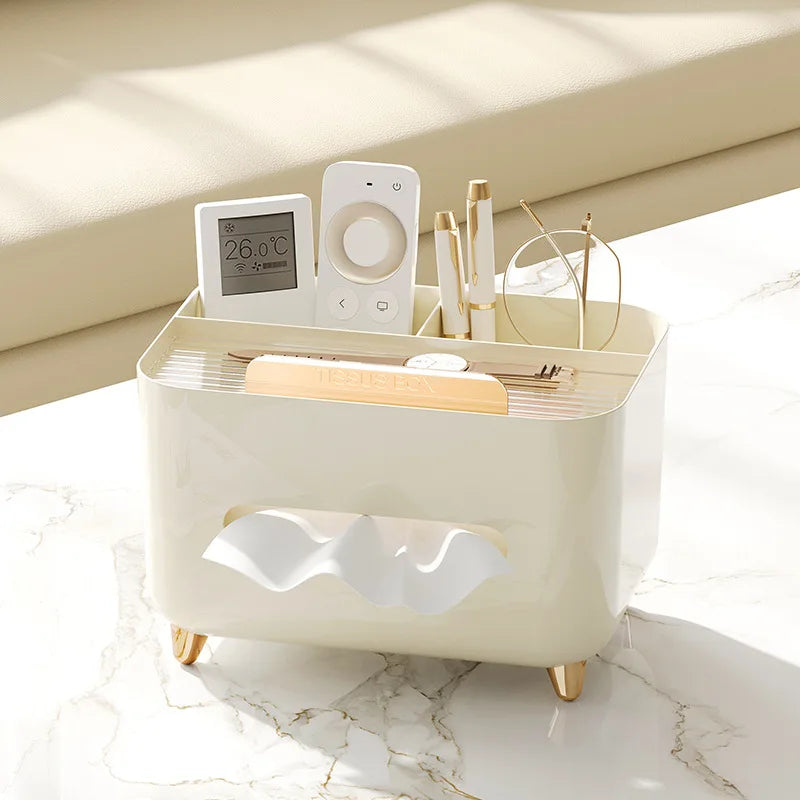 Nutshell multifunctional desk organizer with tissue box in beige holding remote controls, glasses, and pens on marble surface