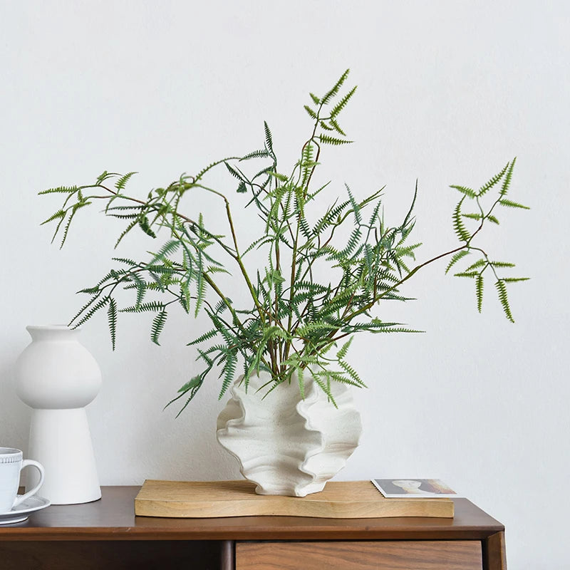 Nordic art coral vase by Nutshell with green fern leaves on wooden table in minimalist room