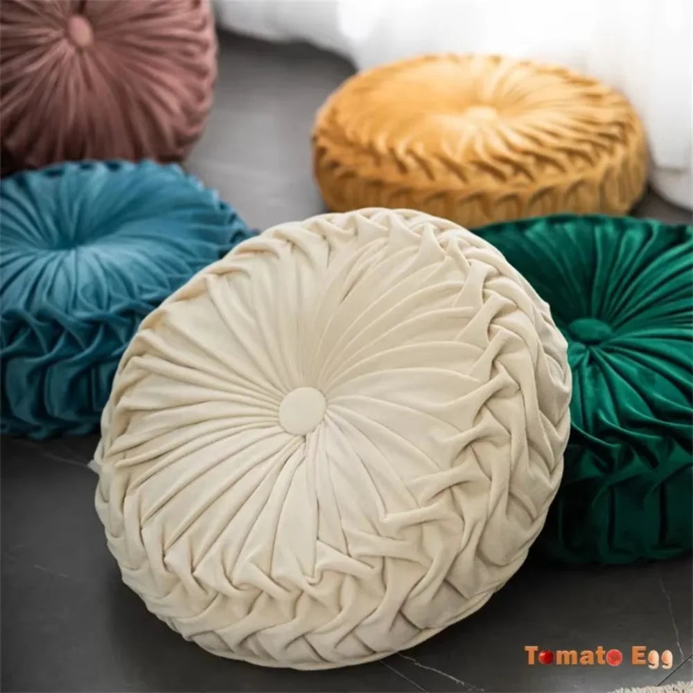 Nutshell round pumpkin pillow cushion in cream with textured pleated design and assorted colorful pillows in background