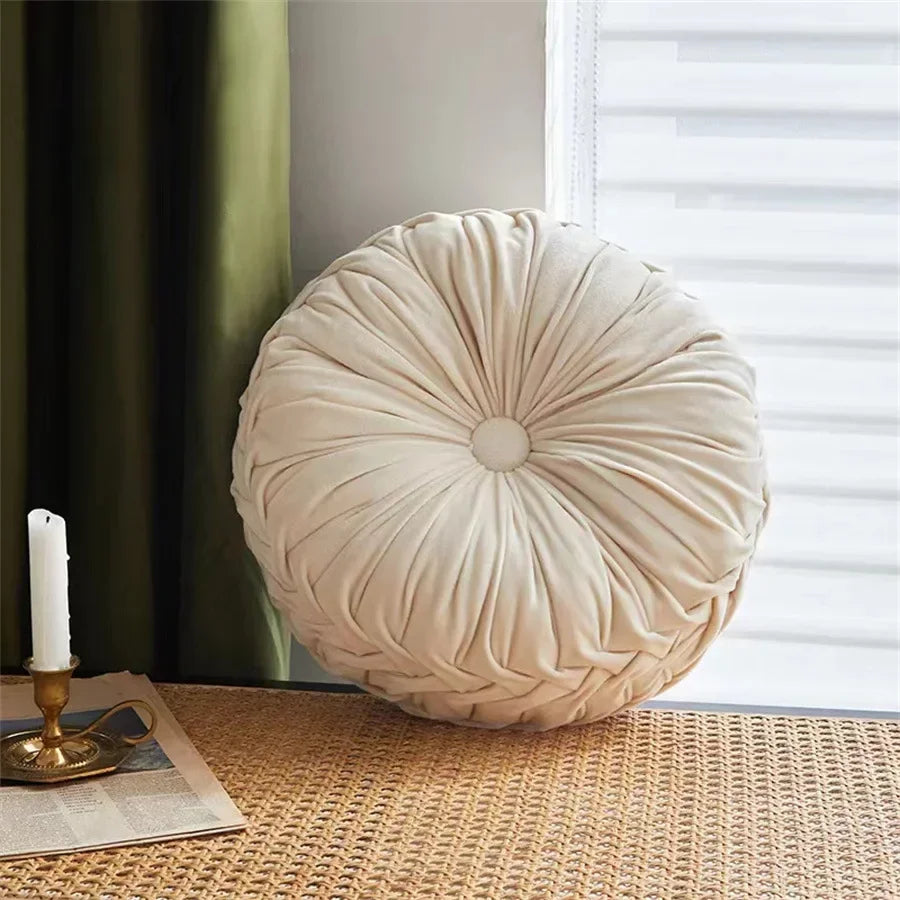 Nutshell round pumpkin pillow cushion in beige placed on a wicker surface near window and candle