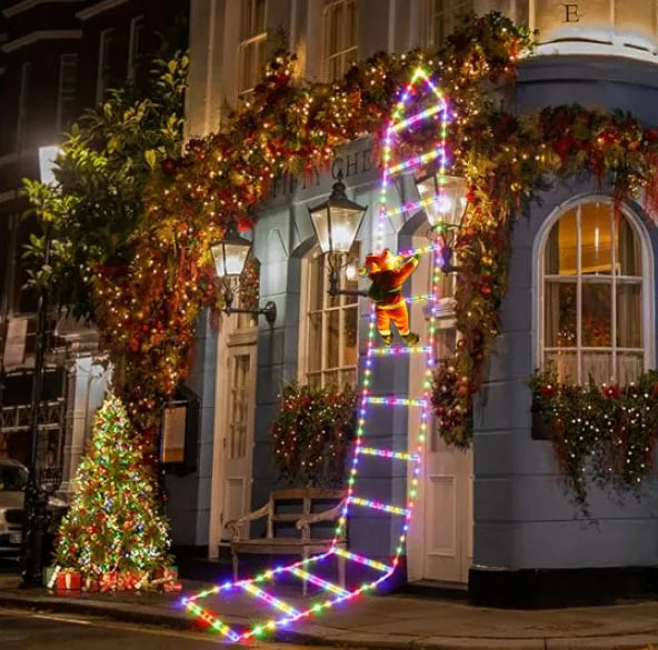 Colorful Santa climbing ladder Christmas decoration with lights and festive garland on a building