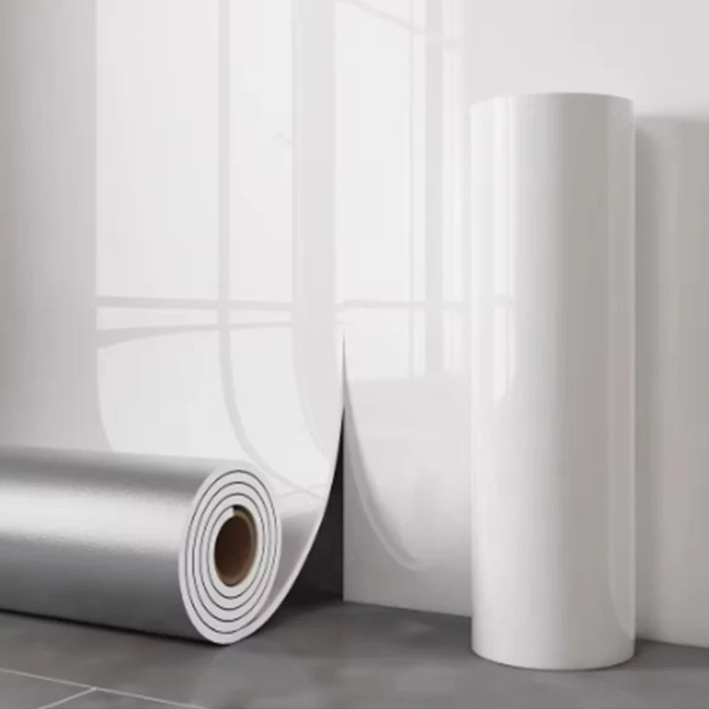 Nutshell glossy white wallpaper rolls leaning on gray tile floor showing backing and shine imitation ceramic tile