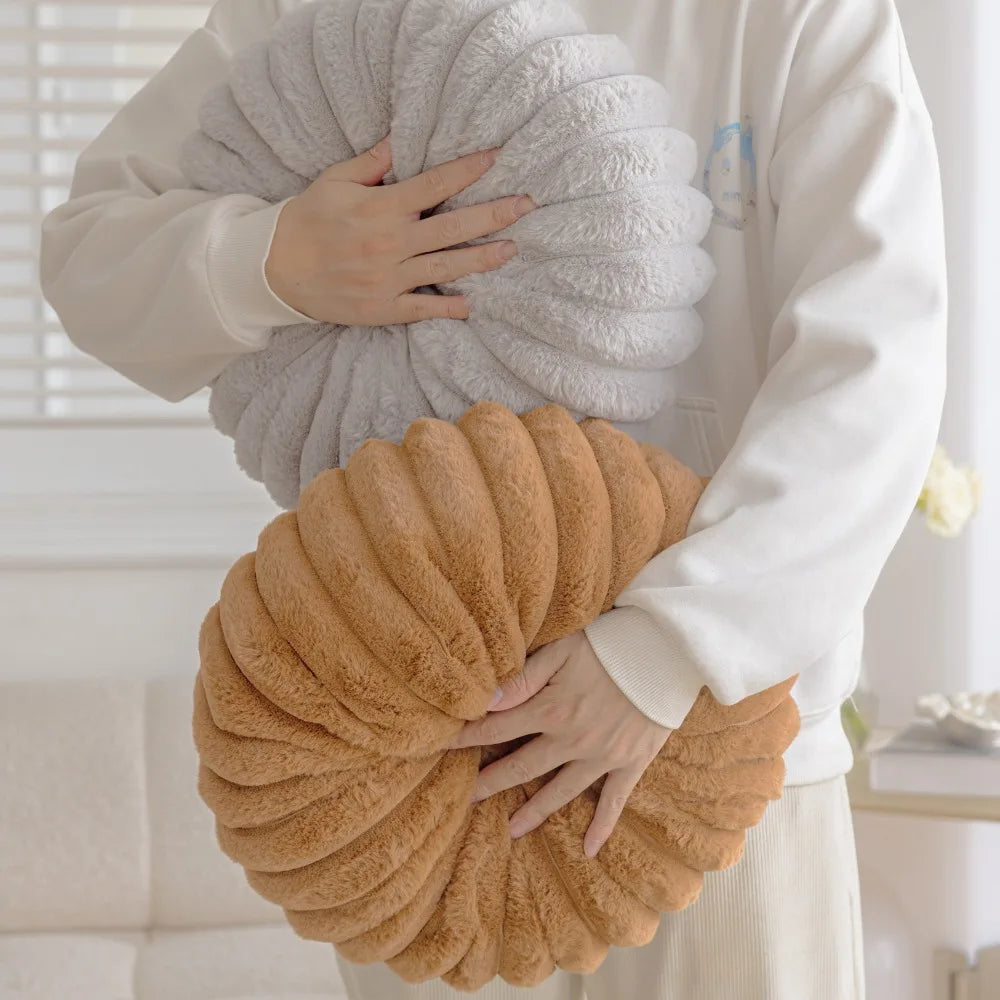 Person holding two soft plush cushions including a round pumpkin pillow in brown and a gray one by Nutshell