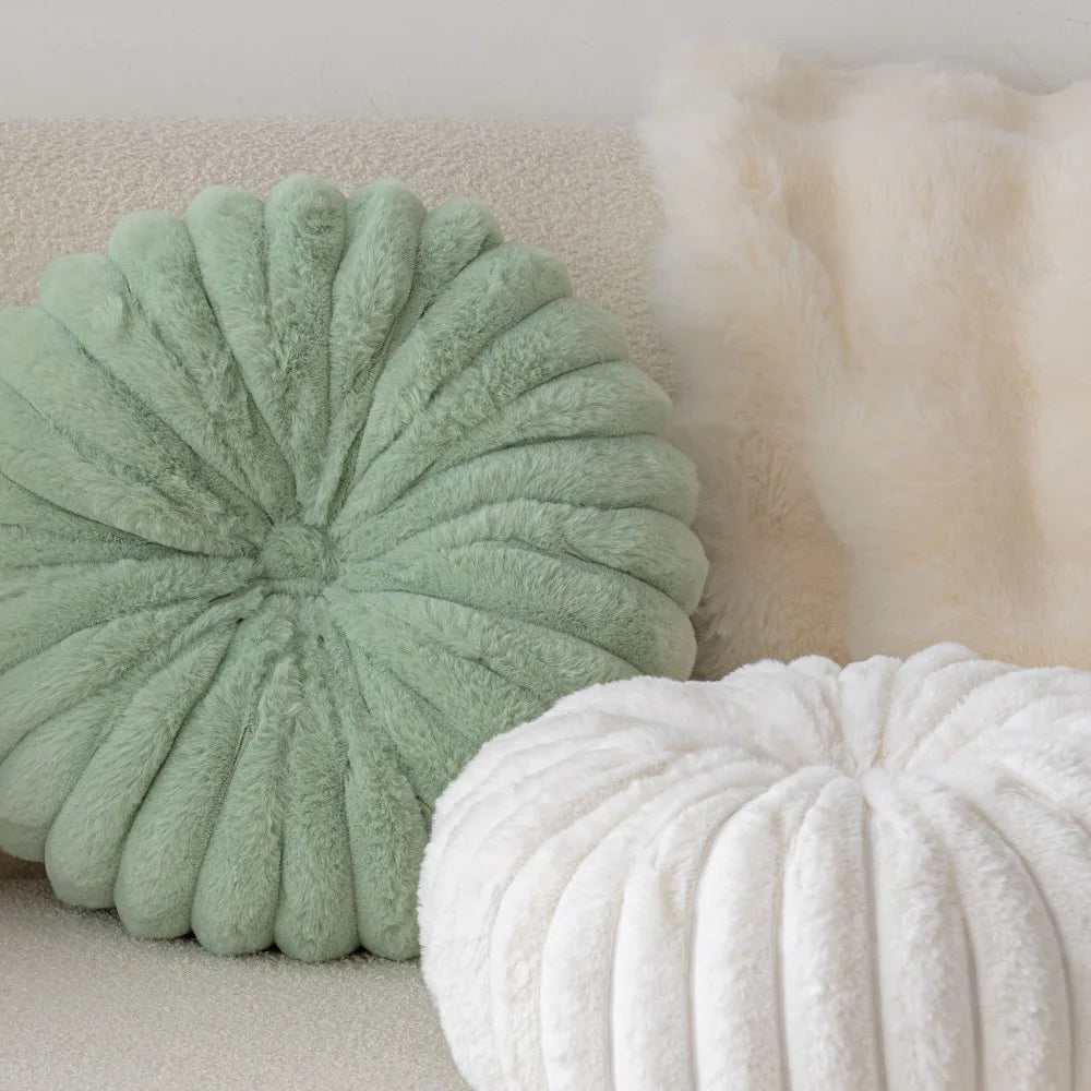 Nutshell soft plush round pumpkin pillow in green and white displayed on a cozy beige sofa