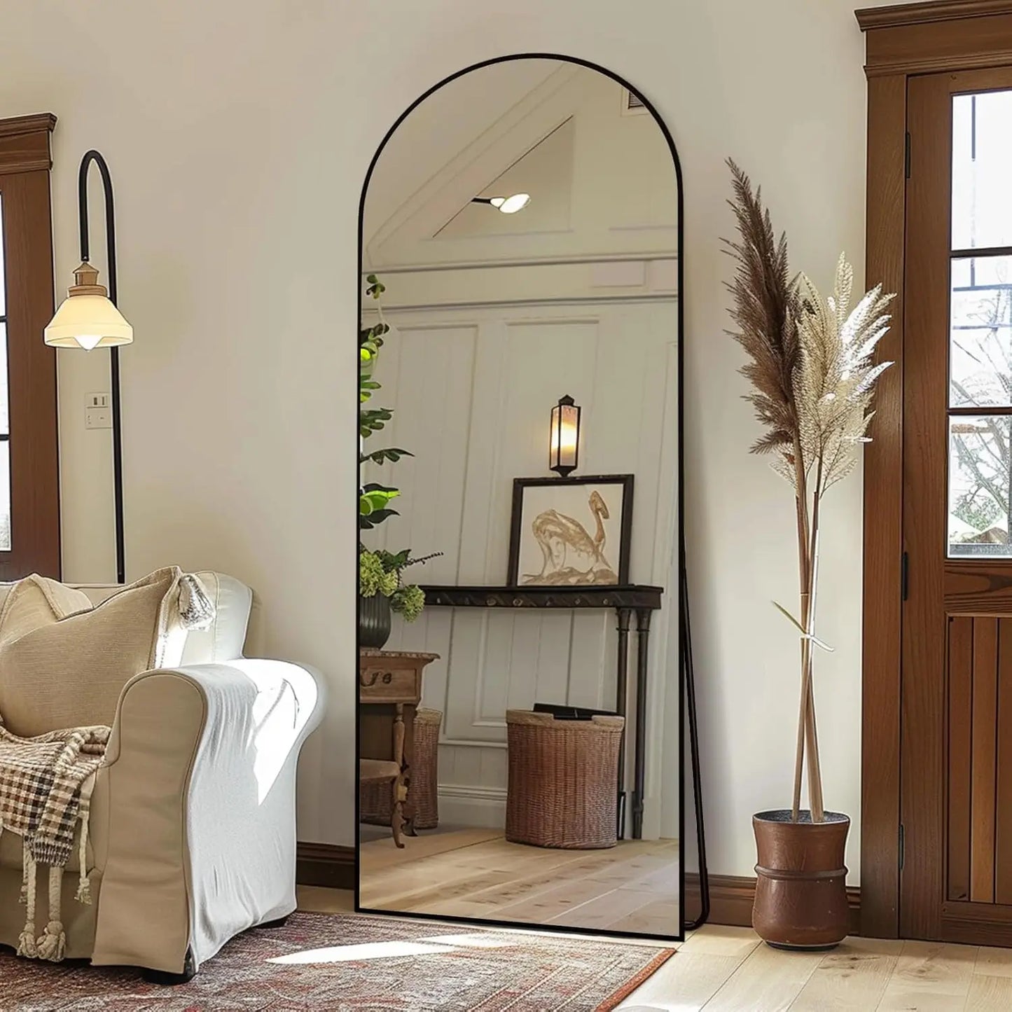 Nutshell arched full length floor mirror with slim black frame leaning on wall in cozy living room reflecting console