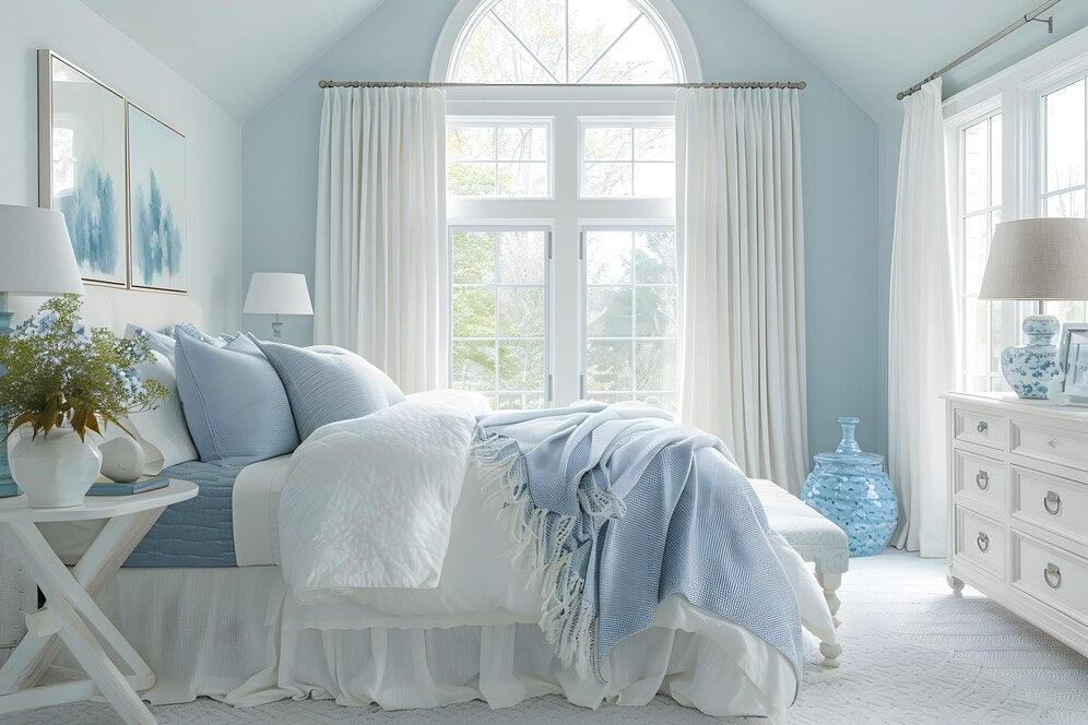 Cozy bedroom featuring light blue decor, soft bedding, and elegant window treatments
