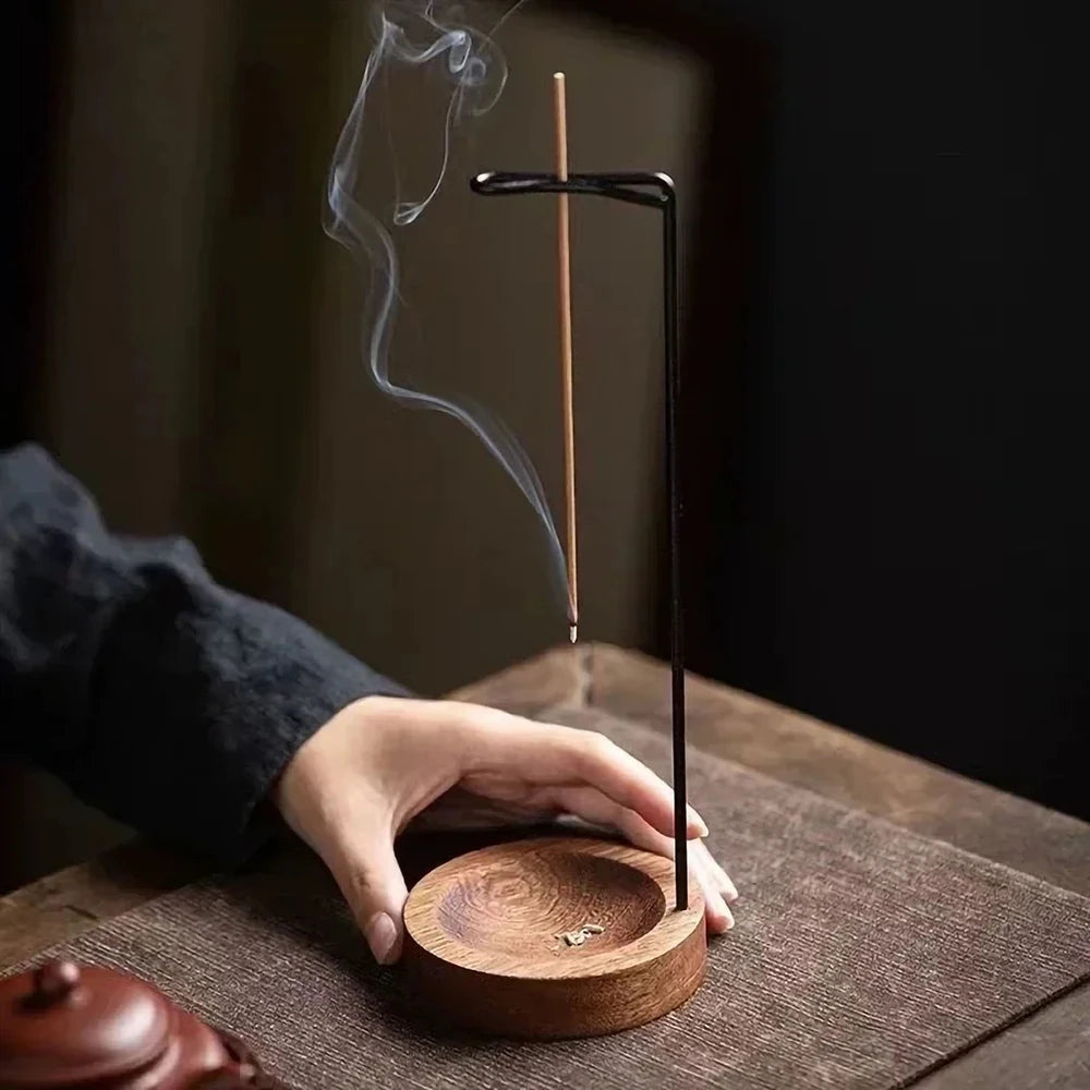 Nutshell anti-ash incense burner with wooden base and metal stand holding a burning incense stick