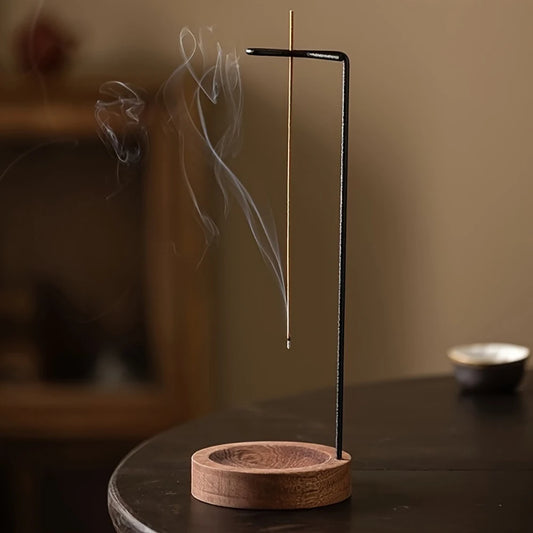 Nutshell anti-ash incense burner with wooden base and black metal stand holding burning incense stick