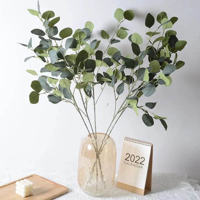 Artificial eucalyptus bouquet displayed in a vase with a calendar in the background