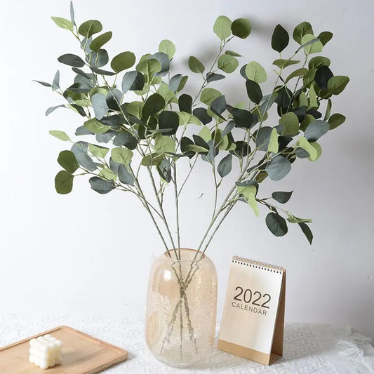 Artificial eucalyptus bouquet displayed in a vase with a calendar in the background