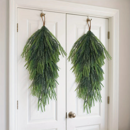 Artificial pine teardrop wreath hanging on white doors for holiday decor and seasonal style