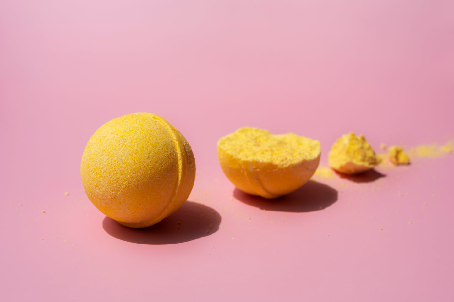 Bright yellow Bath Fizz Bon Bon with a cracked open piece showing its fizzy texture