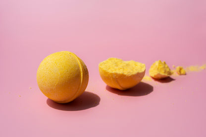 Bright yellow Bath Fizz Bon Bon with a cracked open piece showing its fizzy texture