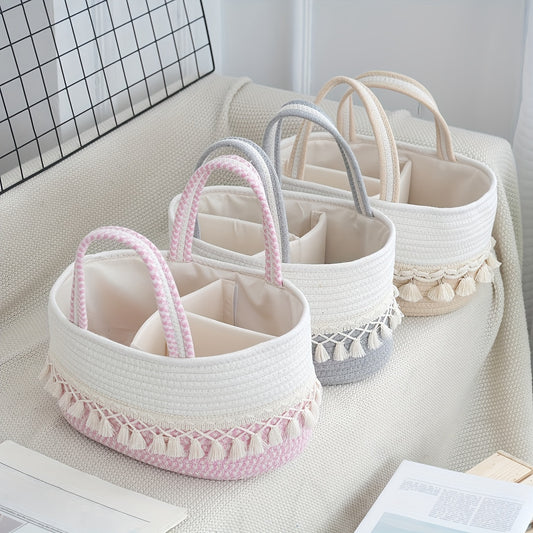 Three boho-chic storage baskets with tassels in pink, grey, and white on a cozy nursery sofa