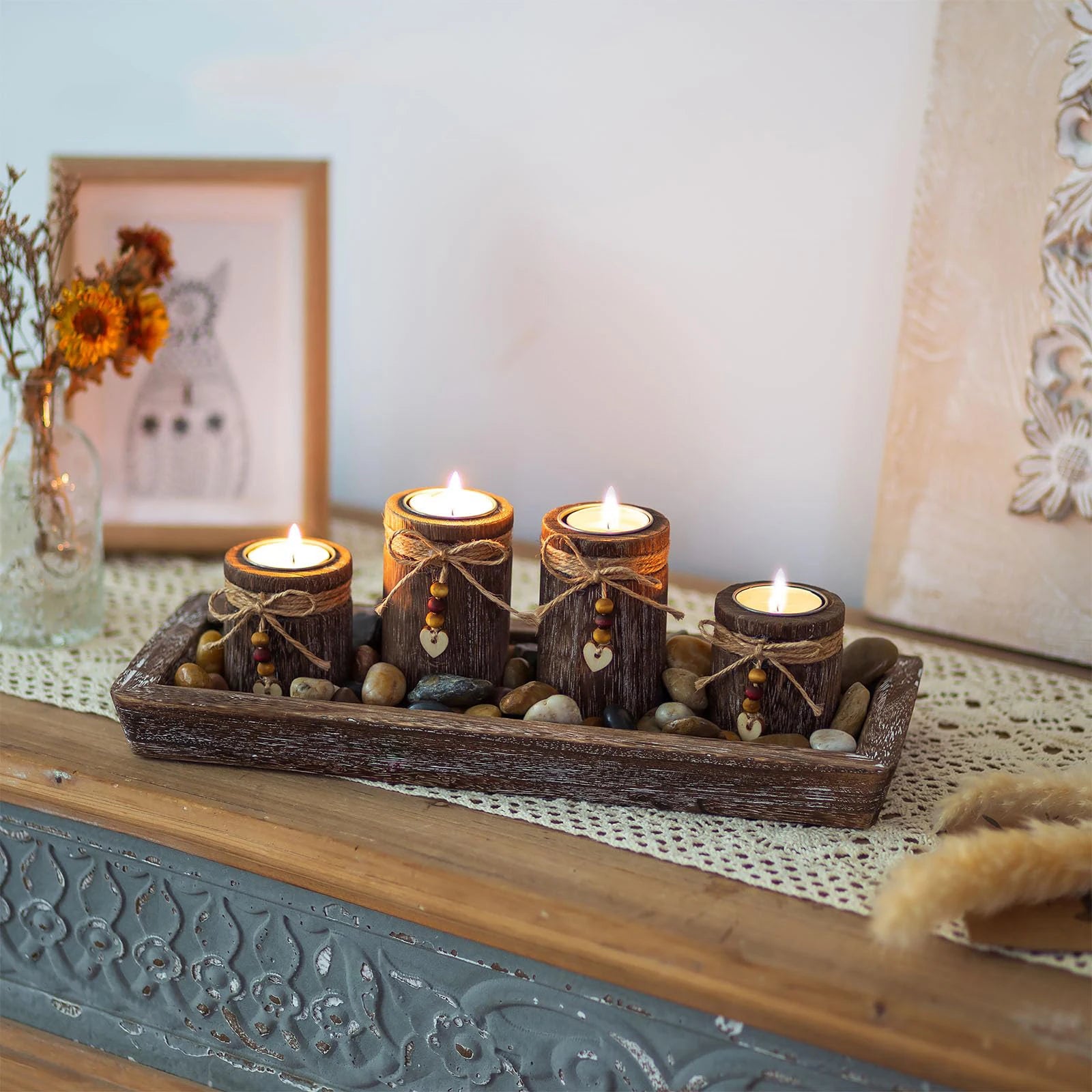 Boho wooden tray candle centerpiece with four lit rustic candles and decorative stones on wooden surface