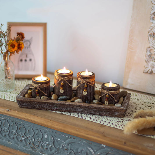 Boho wooden tray candle centerpiece with four lit rustic candles and decorative stones on wooden surface