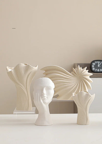 Nutshell ceramic conch design vase displayed with sculptural ceramic vases on white surface