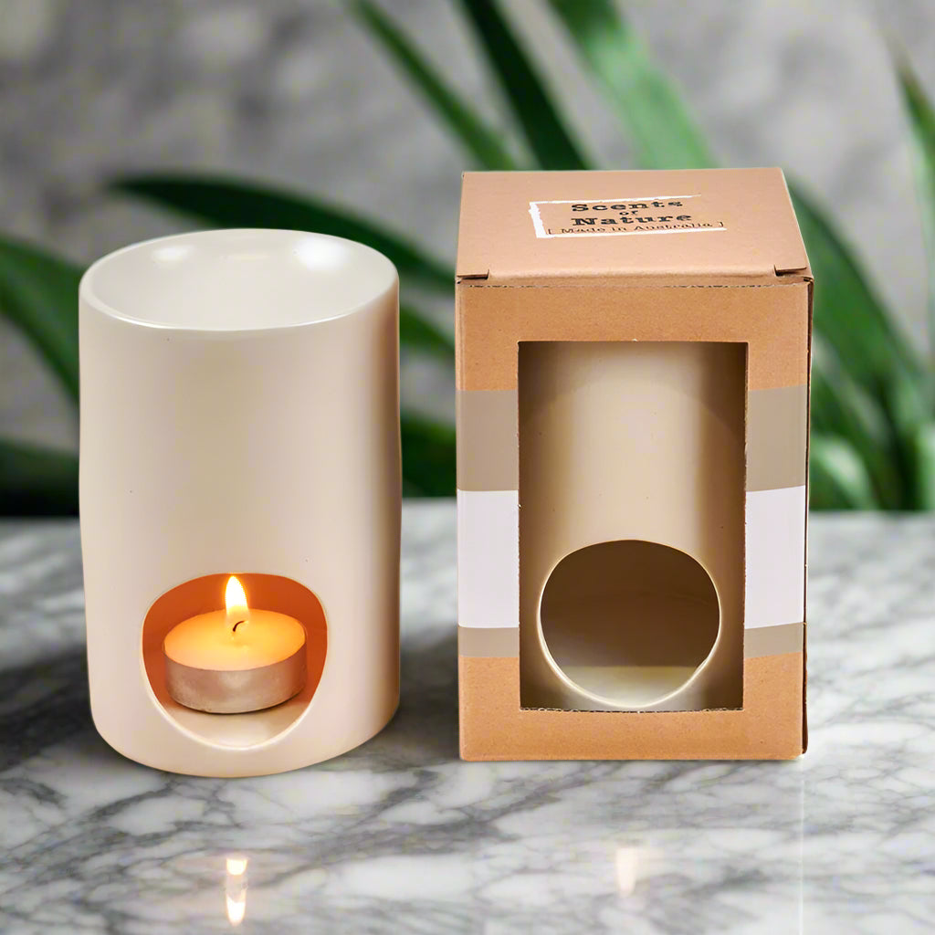 Nutshell ceramic wax melt burner in white with lit tea light and packaging on marble surface