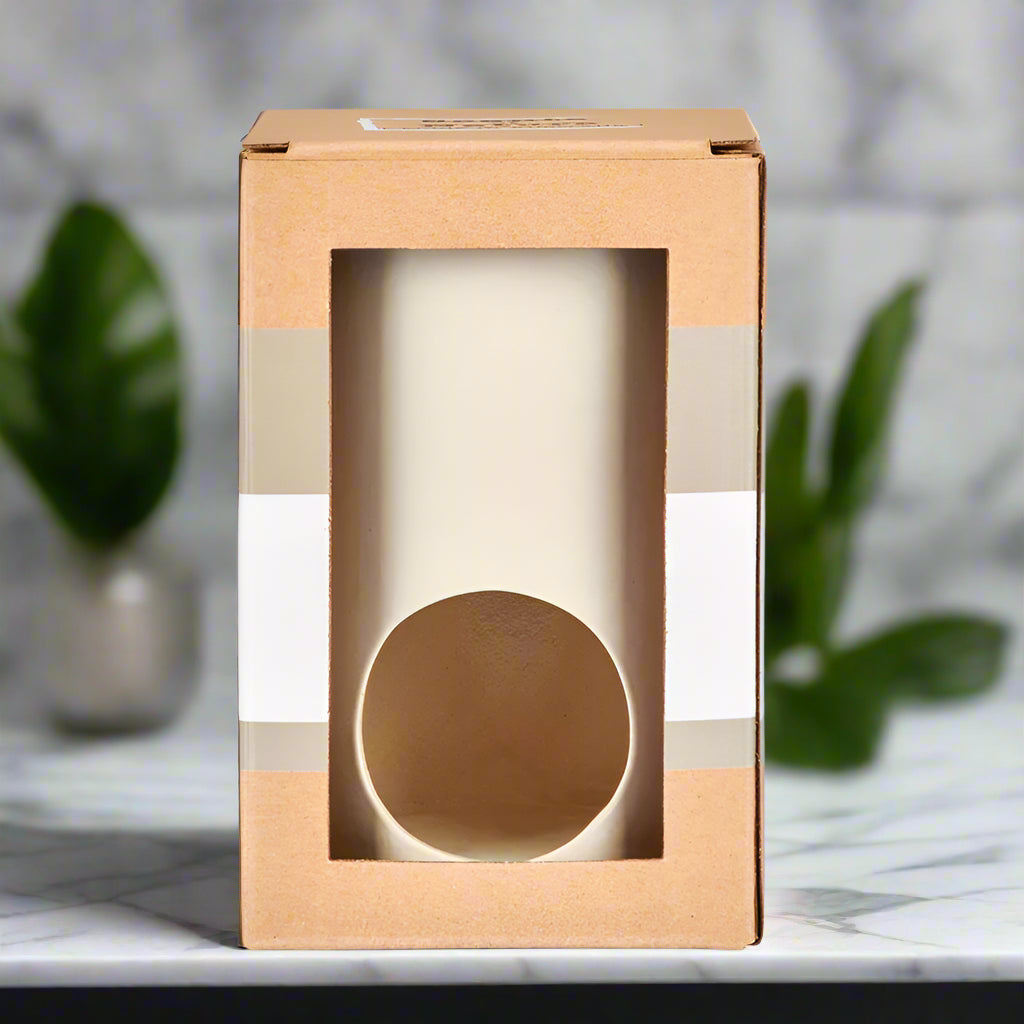 Nutshell ceramic wax melt burner in a brown and white cardboard box on marble surface with greenery background