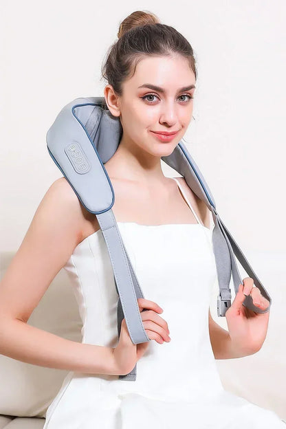 Woman wearing Nutshell 3D kneading neck massager with heat in gray over shoulders holding straps