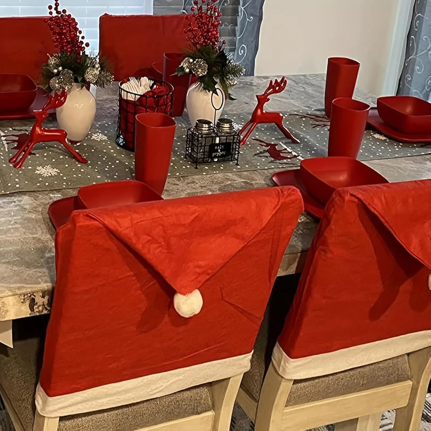 Festive Christmas Hat Chair Covers on Dining Chairs at a Holiday Table Setting