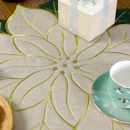 Elegant Christmas holly leaf placemat in gold and green with a decorative setting of dishes and a gift box