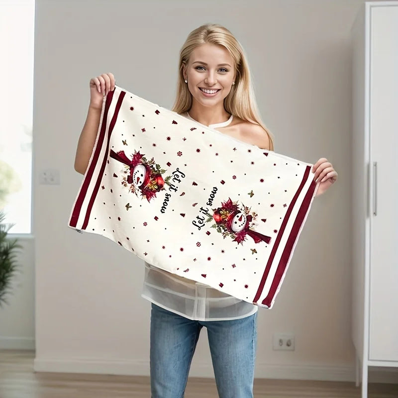 Smiling woman holding a festive Christmas kitchen towels set decorated with snowmen and holiday motifs
