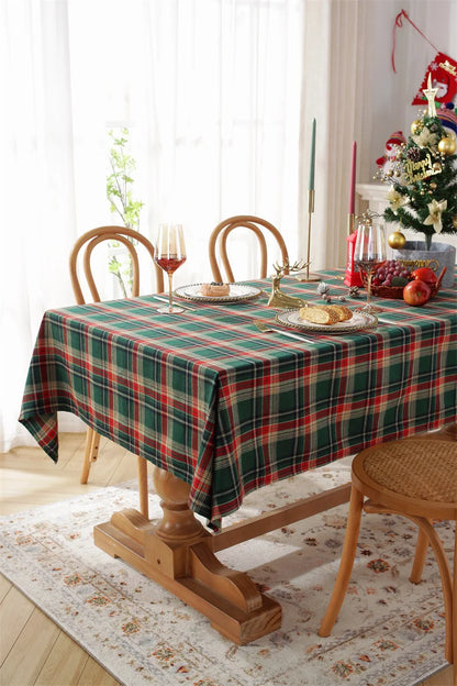 Christmas Plaid Tablecloth in red and green on a wooden table set for a festive holiday meal