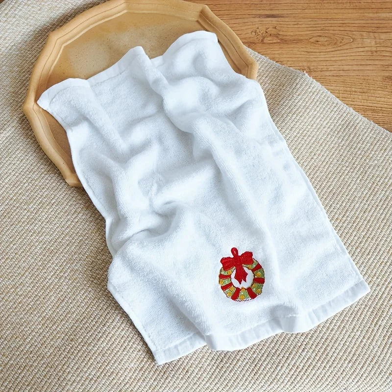 Christmas themed hand towels featuring a decorative embroidered wreath design on soft white fabric