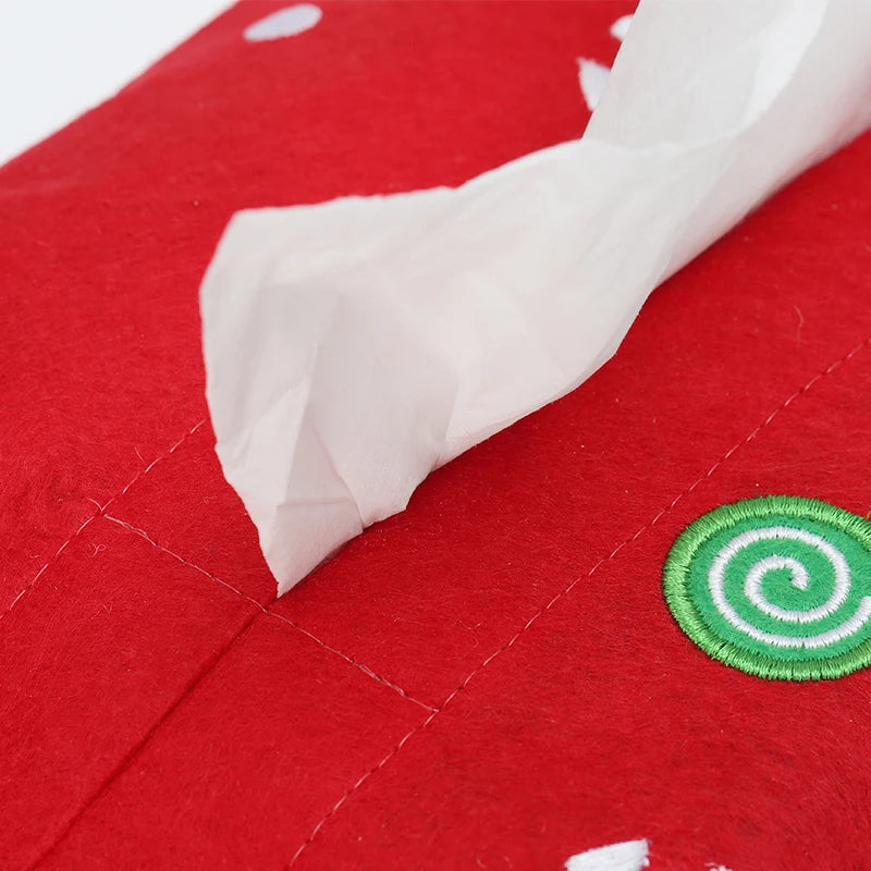 Red Christmas tissue box cover with festive design and a tissue partially pulled out