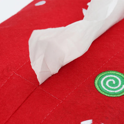 Red Christmas tissue box cover with festive design and a tissue partially pulled out