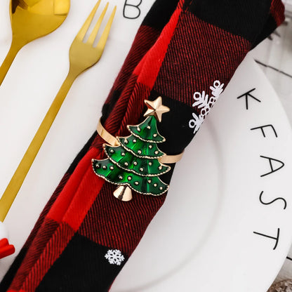 Festive Christmas tree napkin rings with a gold finish and green embellishments on a plaid napkin
