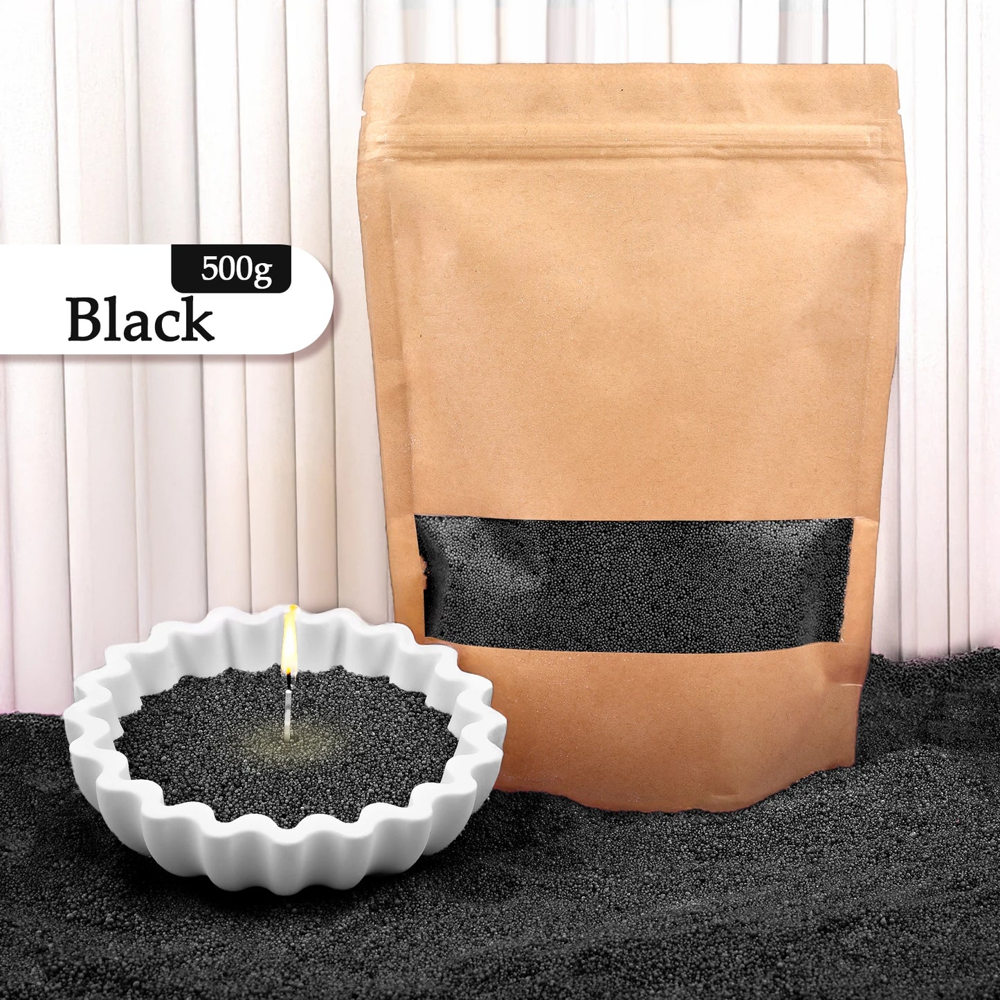 Nutshell black colored candle sand 500g in resealable brown bag with lit candle in white ceramic holder