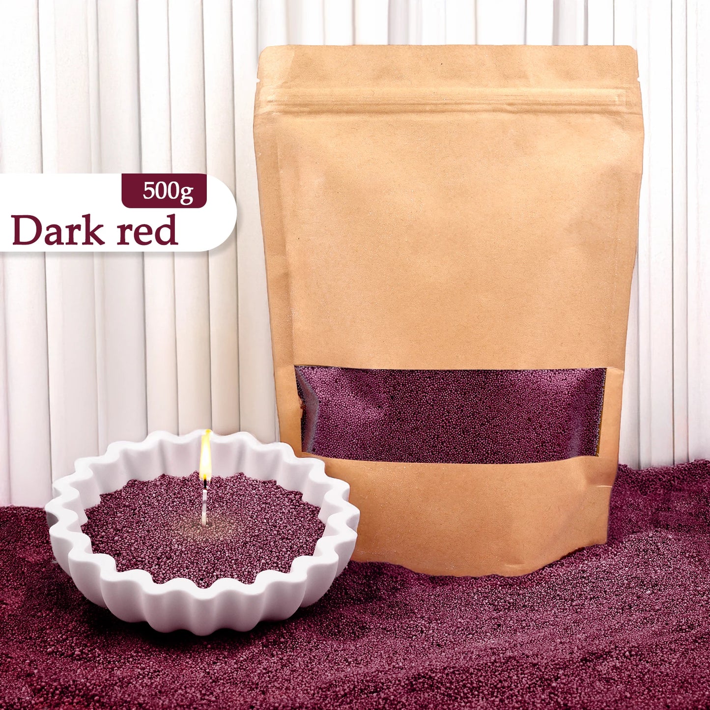 Nutshell dark red colored candle sand 500g in a brown resealable bag with a white candle filled with sand burning